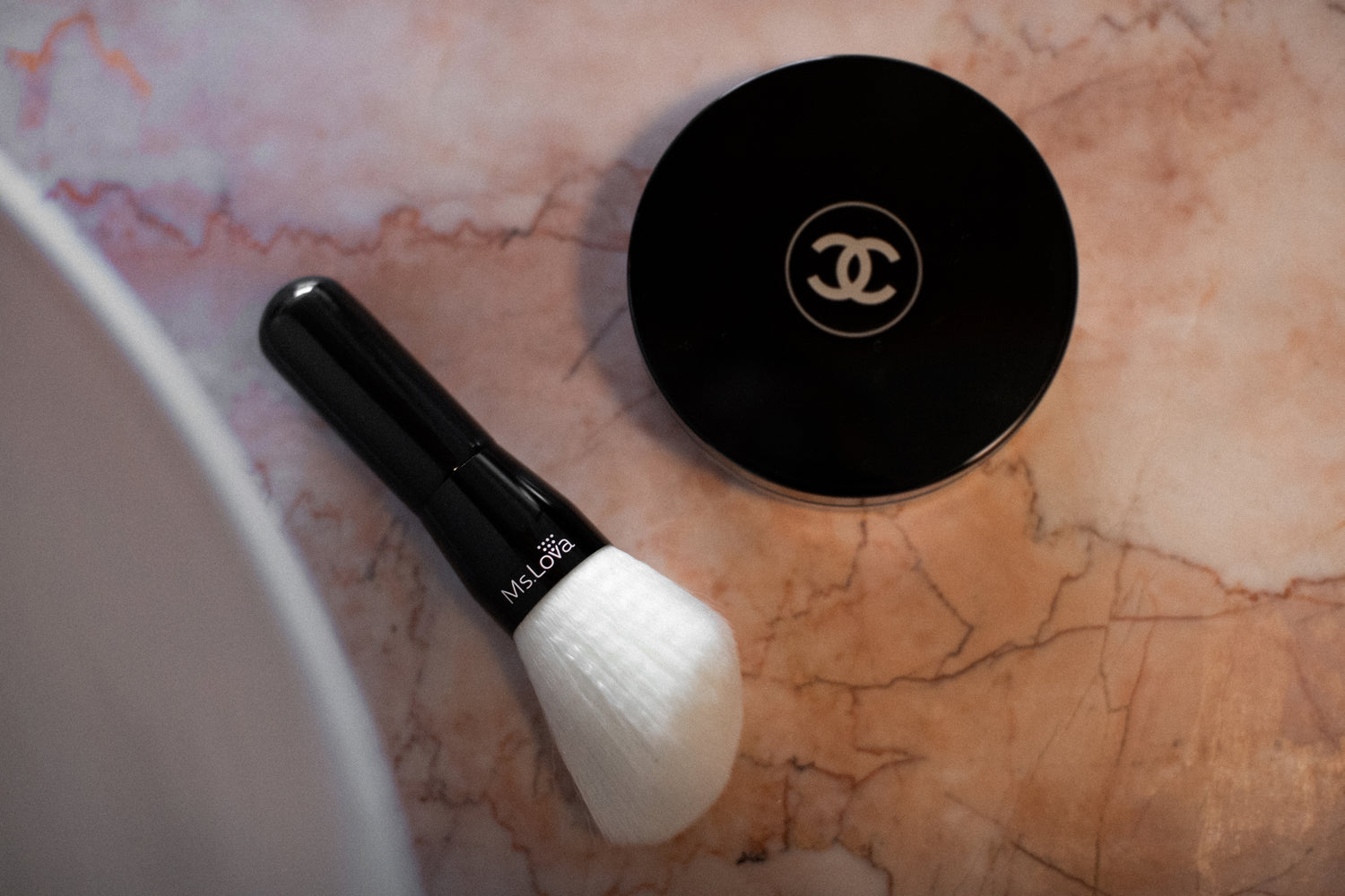 Ms.Lova blending brush beside luxury makeup compact on marble surface