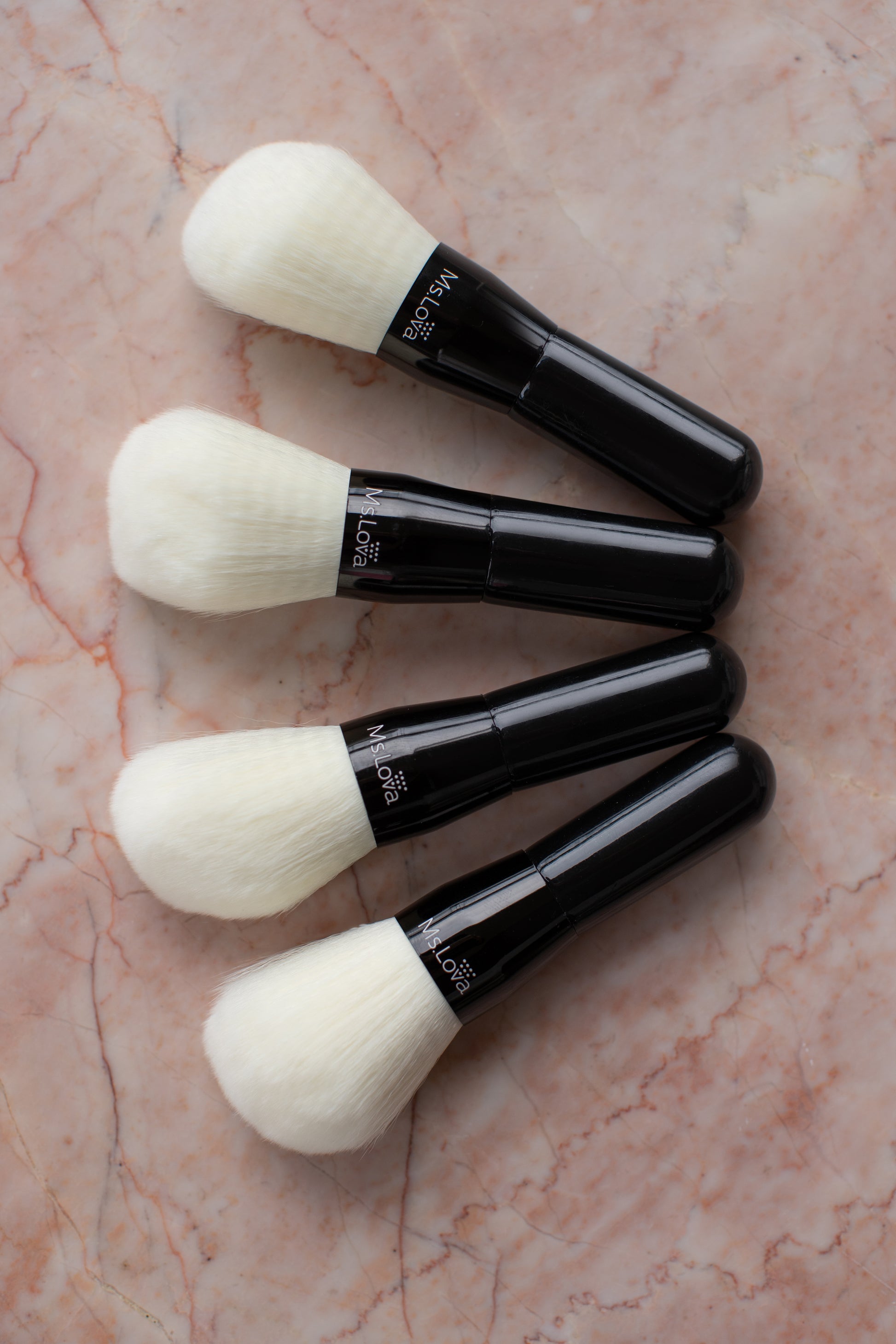 Collection of Ms.Lova self-tan blending brushes on pink marble background
