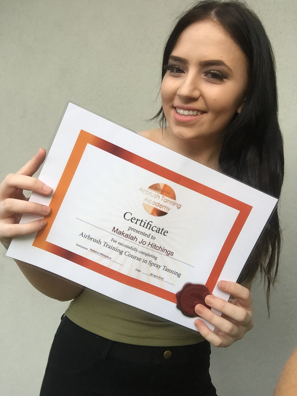 Student holding certificate after completing Ms.Lova private hands-on spray tan training in Sydney.